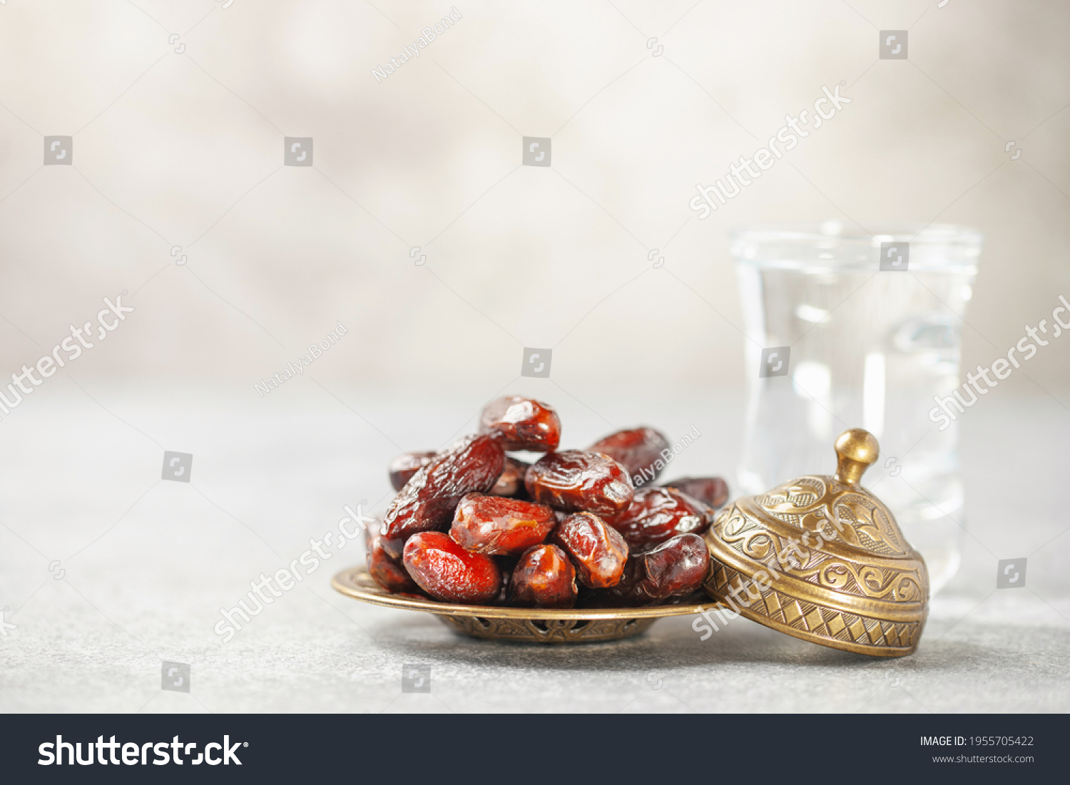 A glass of water and dry dates on saucer ready to eat for iftar time. Islamic religion and ramadan concept. #1955705422