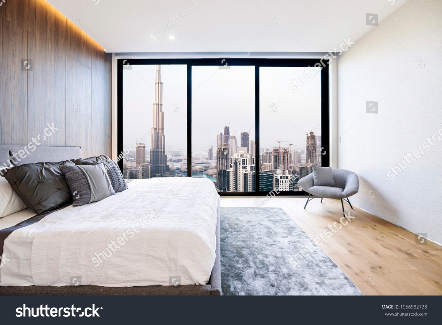 Modern and luxurious bedroom with white ceiling and wood accents with views of tall building and downtown Dubai skyline. Condo or Hotel accomodation. #1956982738