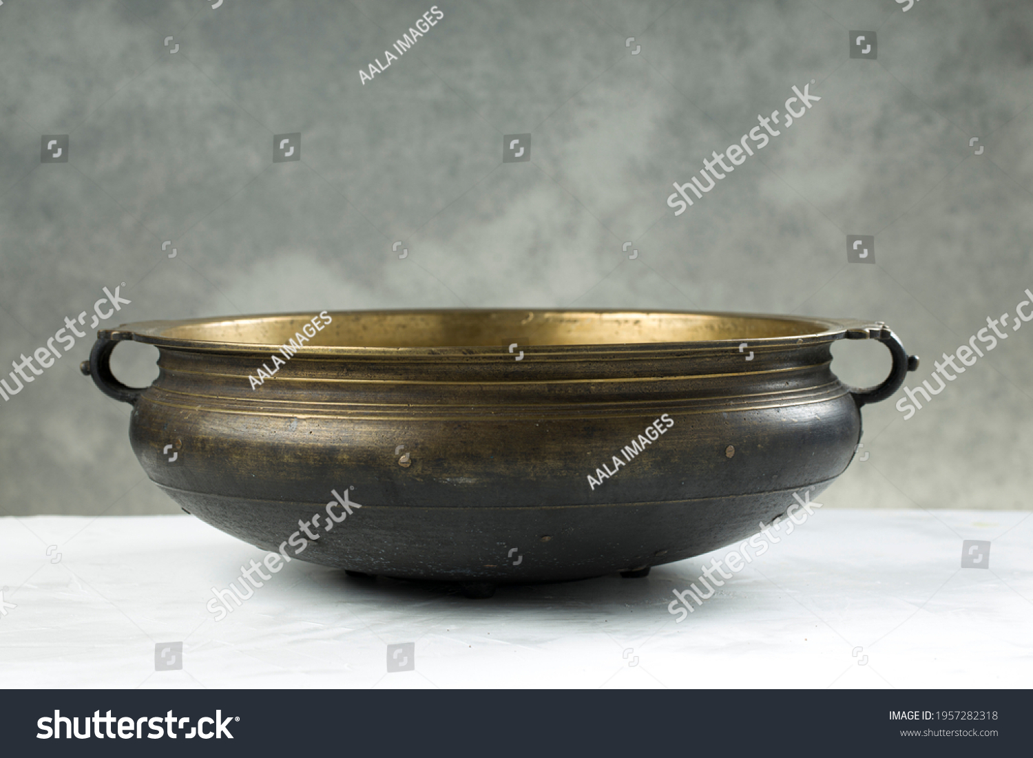 Urule or Brass vessel,an empty traditional  south Indian cooking vessel which is an antique piece placed on grey textured background. #1957282318