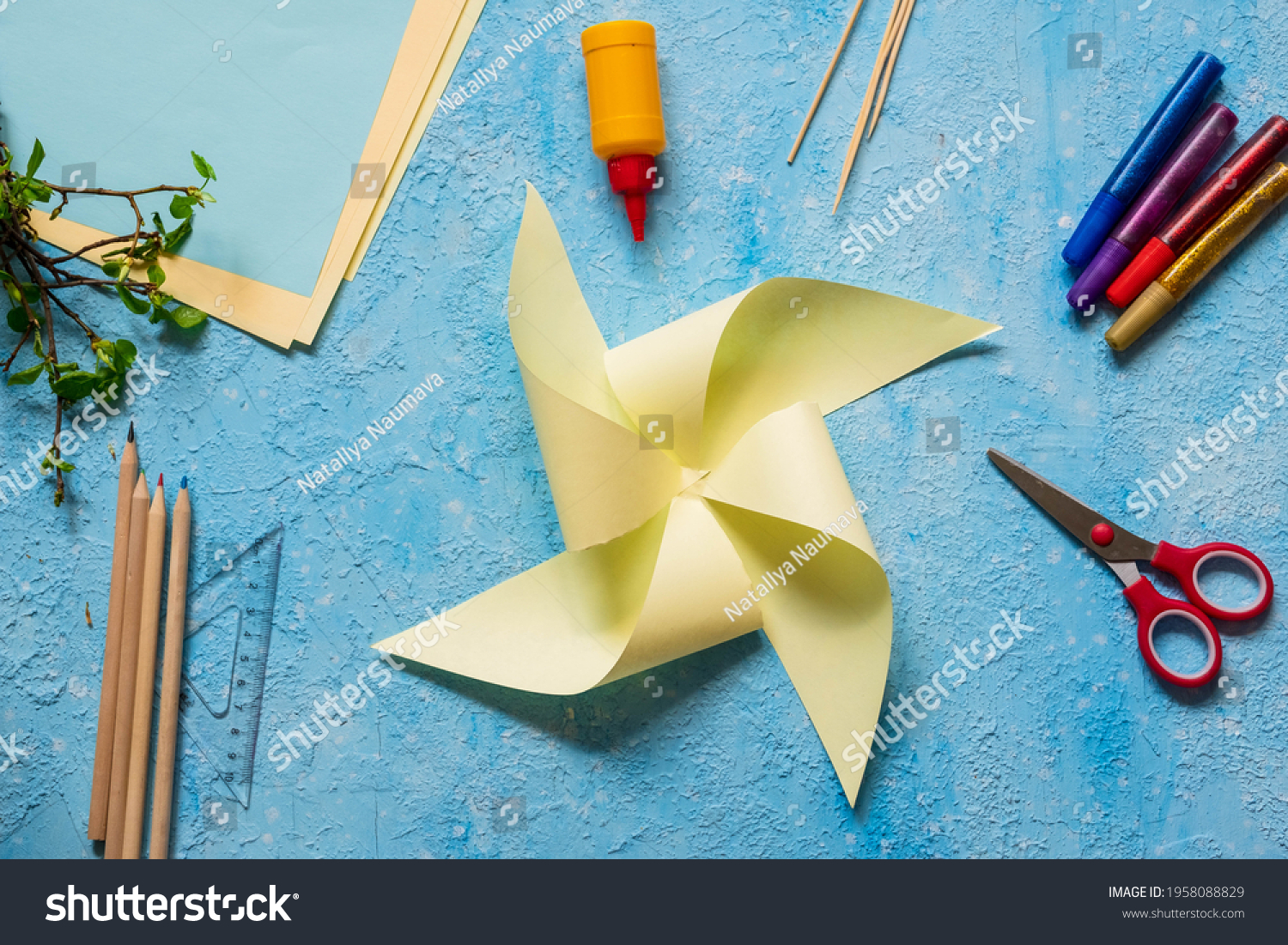 Step-by-step making of a paper weather vane by a child on a blue concrete background. Children's creativity, divas, crafts. Paper crafts #1958088829