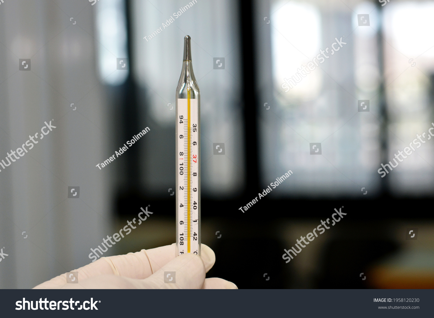 a medical personnel holding an armpit mercury temperature measuring thermometer  #1958120230