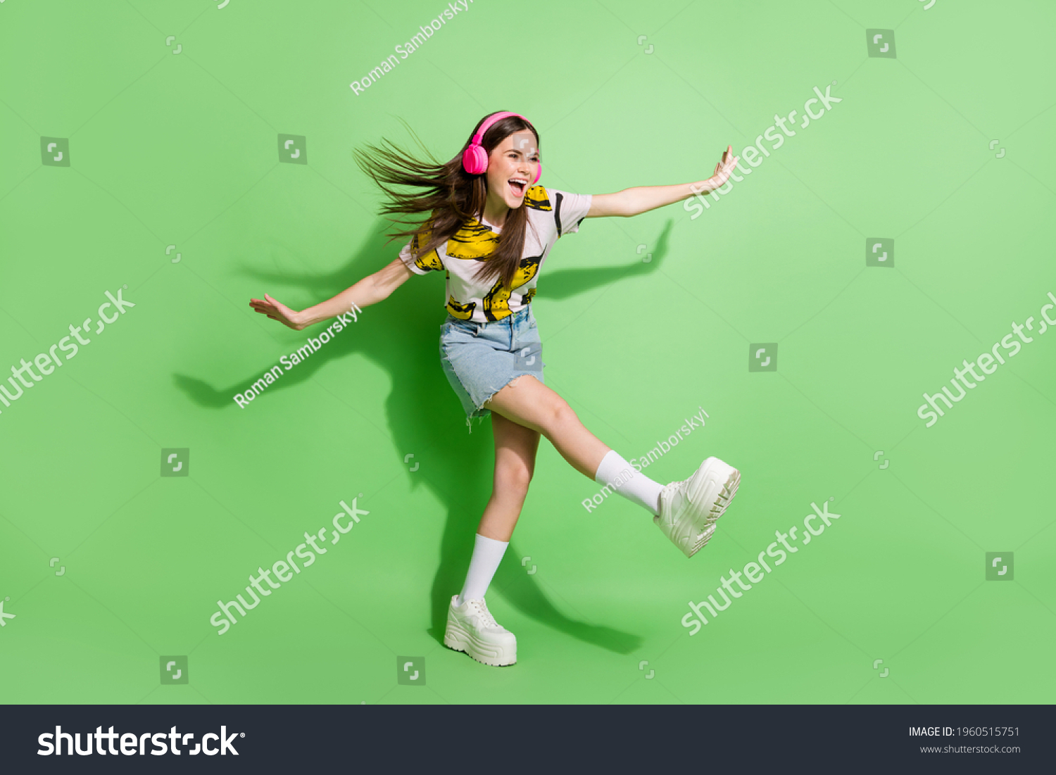 Full body photo of brunette dreamy young woman look empty space hands wings dance wear headphones isolated on green color background #1960515751