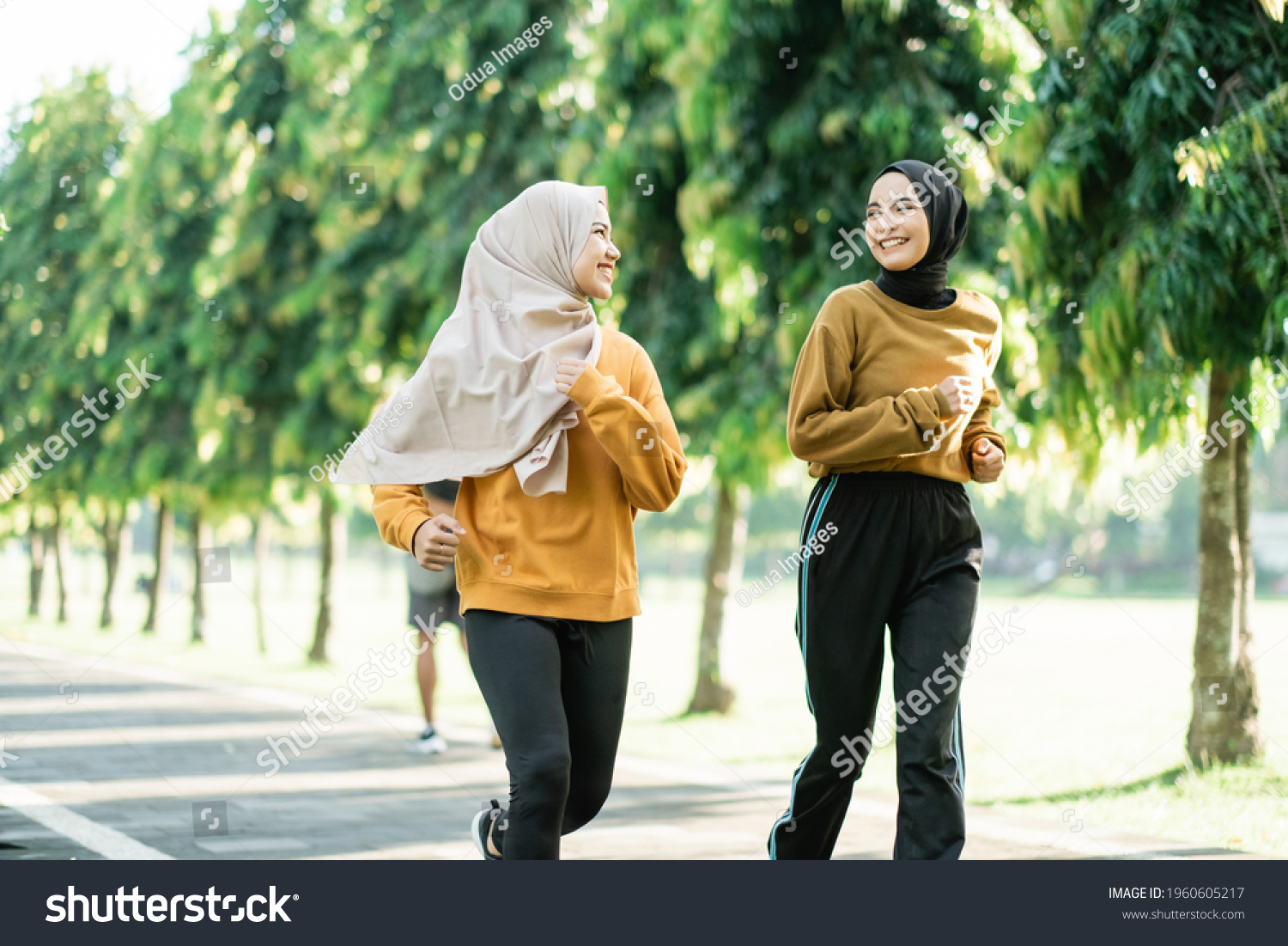 two asian muslim girls enjoy jogging together while chatting in the afternoon in the garden field #1960605217