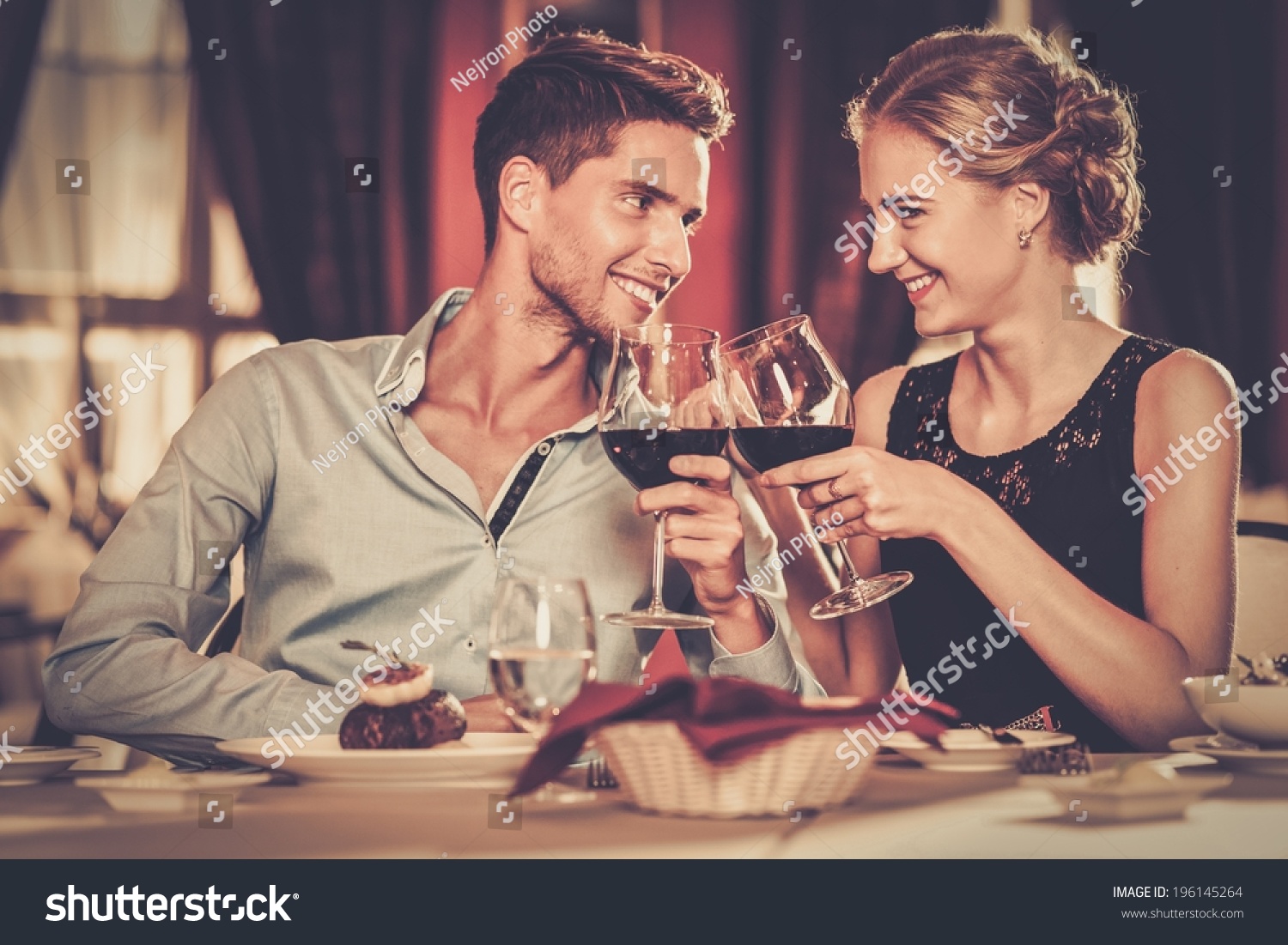 Beautiful young couple with glasses of red wine in luxury restaurant #196145264