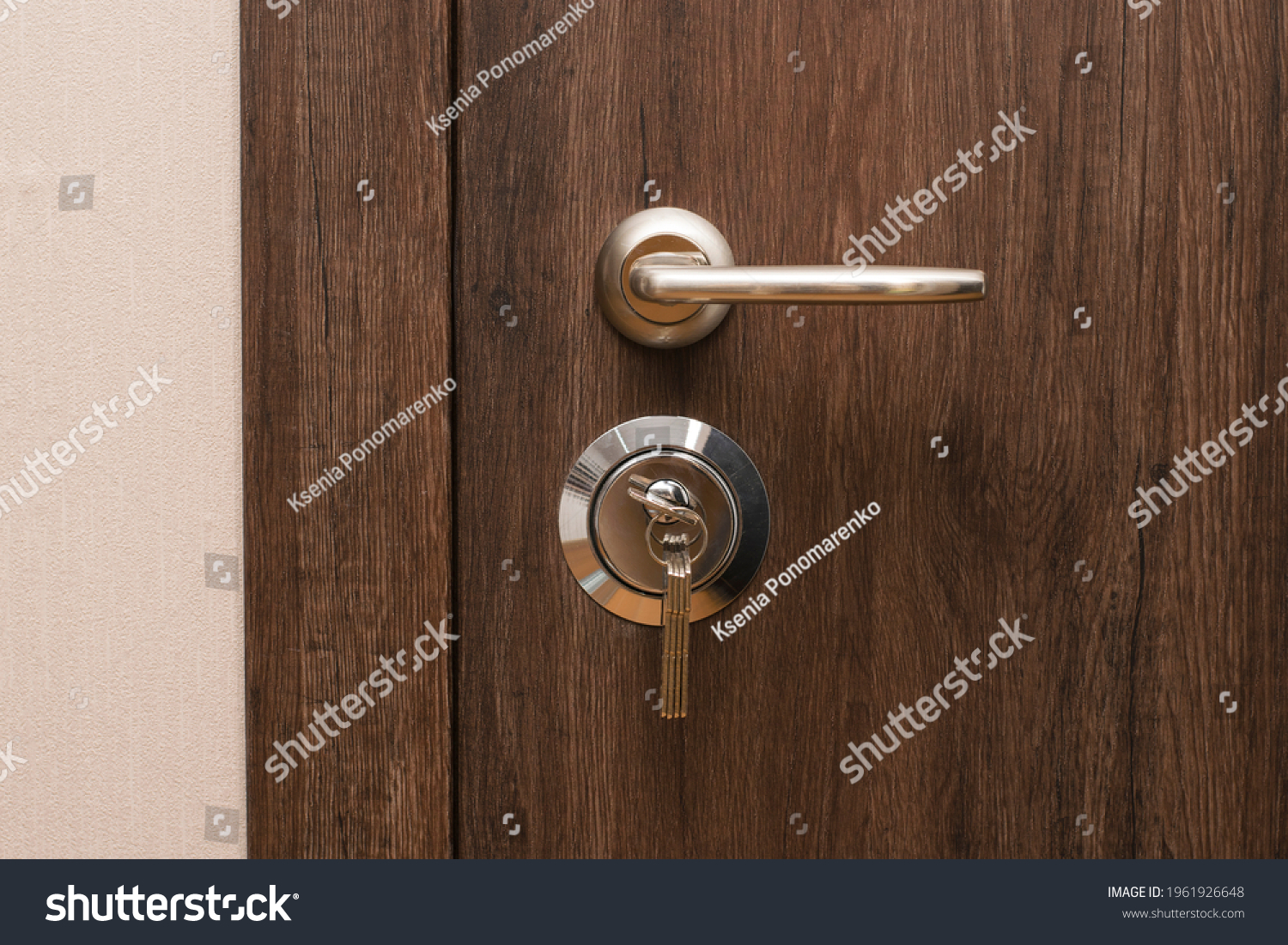 Door handle and lock with keys close-up. Closed modern entrance door in oak color. #1961926648