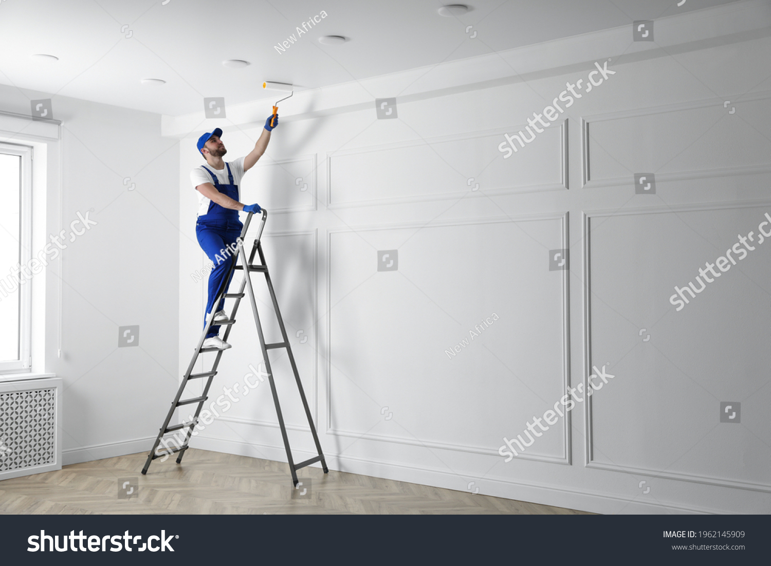 Handyman painting ceiling with white dye indoors, space for text #1962145909