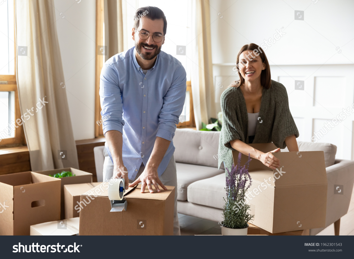 Portrait of smiling young Caucasian couple renters pack boxes packages relocate together. Happy man and woman tenants seal parcels moving to new home. Relocation, rental, rent concept. #1962301543
