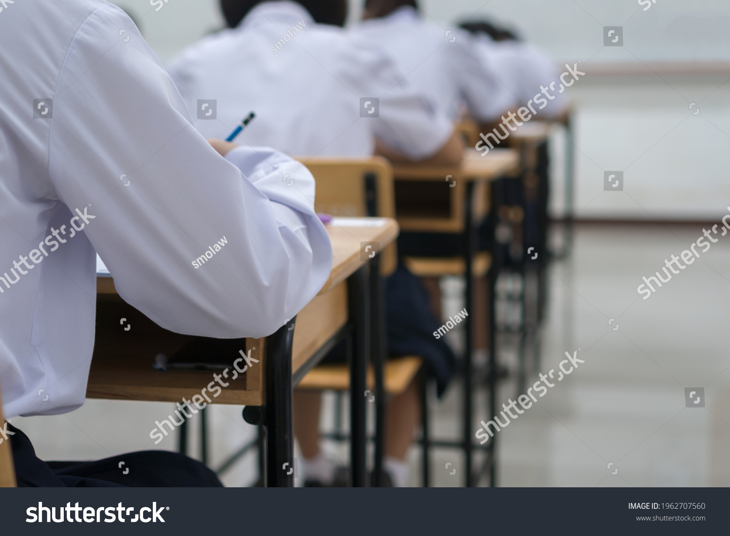 Writing test in exam with behind girl Asian students group concentrate in high school, serious taking final examination desk at classroom with Thai student uniform. Education evaluation back to school #1962707560