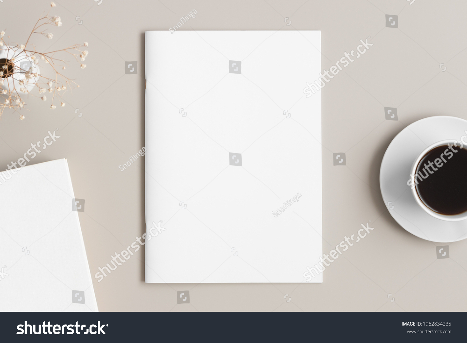 Magazine mockup with a cup of coffee, book and a gypsophila on the beige table. #1962834235