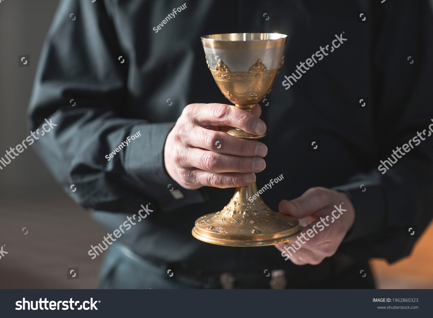 Close-up of senior priest holding the cup in the church #1962860323
