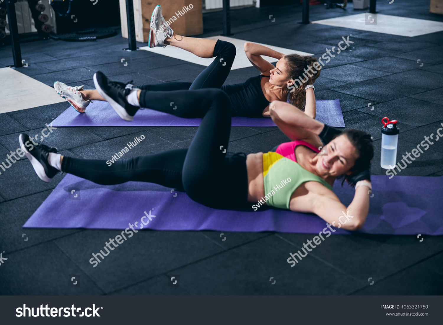 Serious lady and her personal trainer working their abdominal muscles #1963321750
