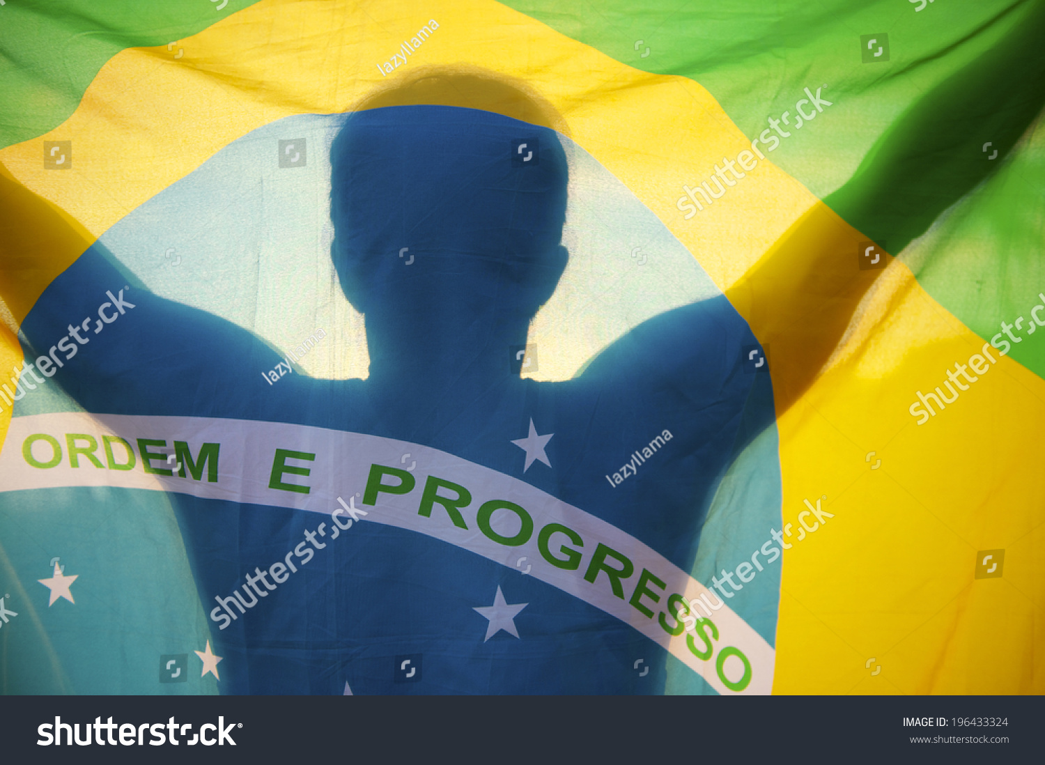 Shadow silhouette of man holding Brazilian flag backlit by bright sun #196433324