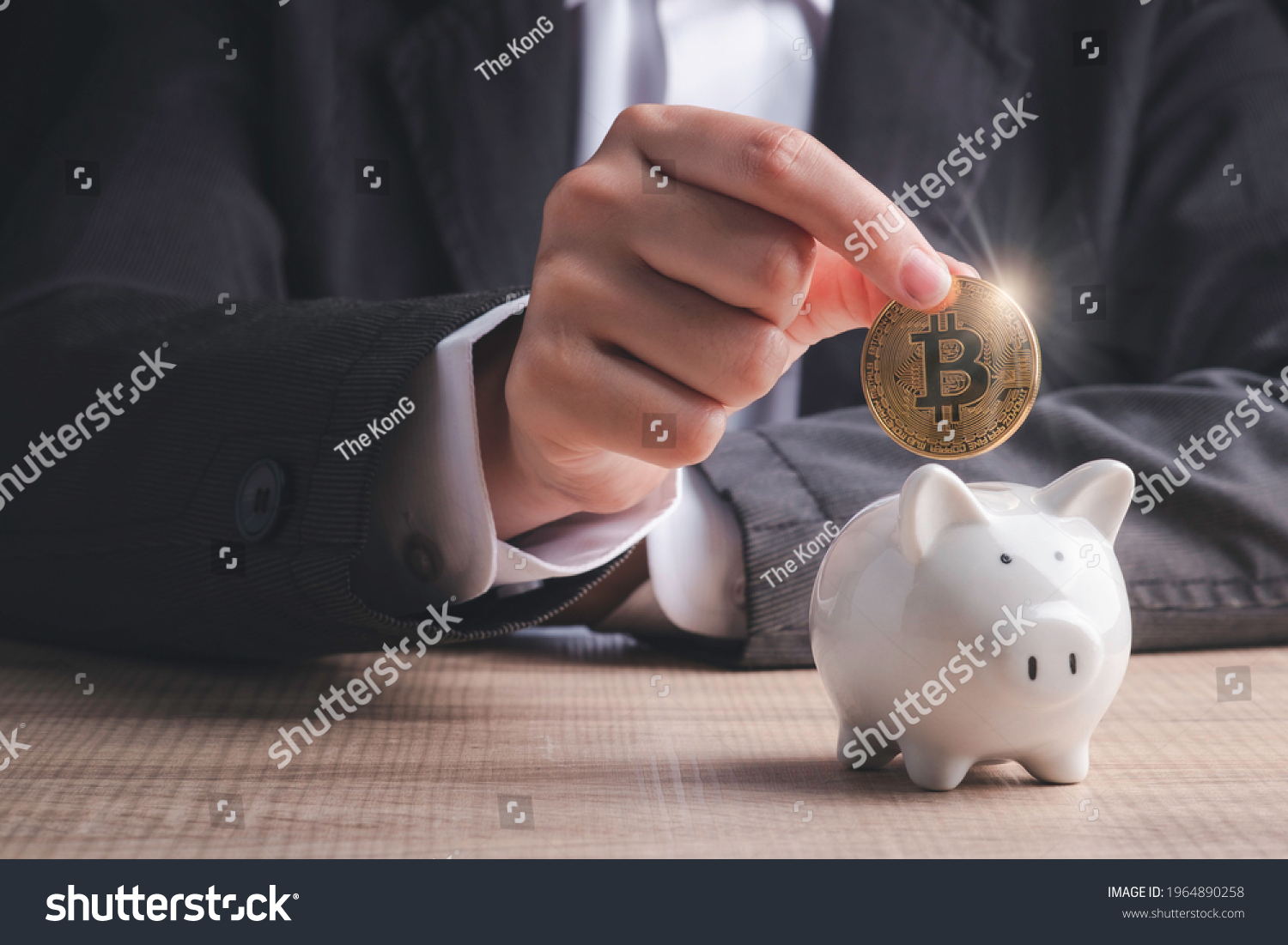 Bitcoin investment concept. Businessman hand holding gold coin cryptocurrency digital money  putting into  piggy bank  on table in black background. #1964890258