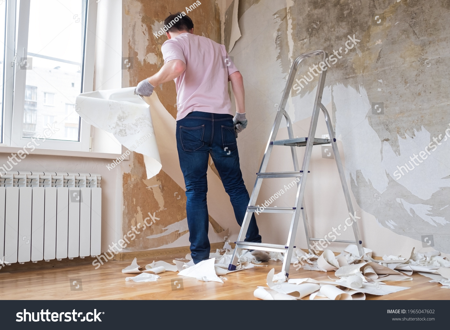 Caucasian man tearing off old wallpaper from wall preparing for home redecoration #1965047602