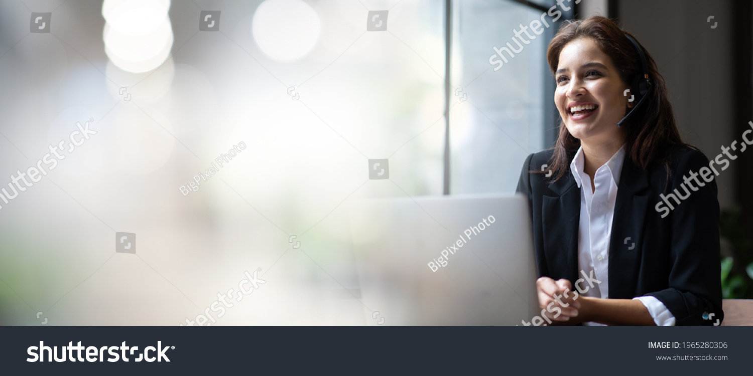 Attractive business woman Asian in suits and headsets are smiling while working with computer at office. Customer service assistant working in office. VOIP Helpdesk headset. panorama banner background #1965280306