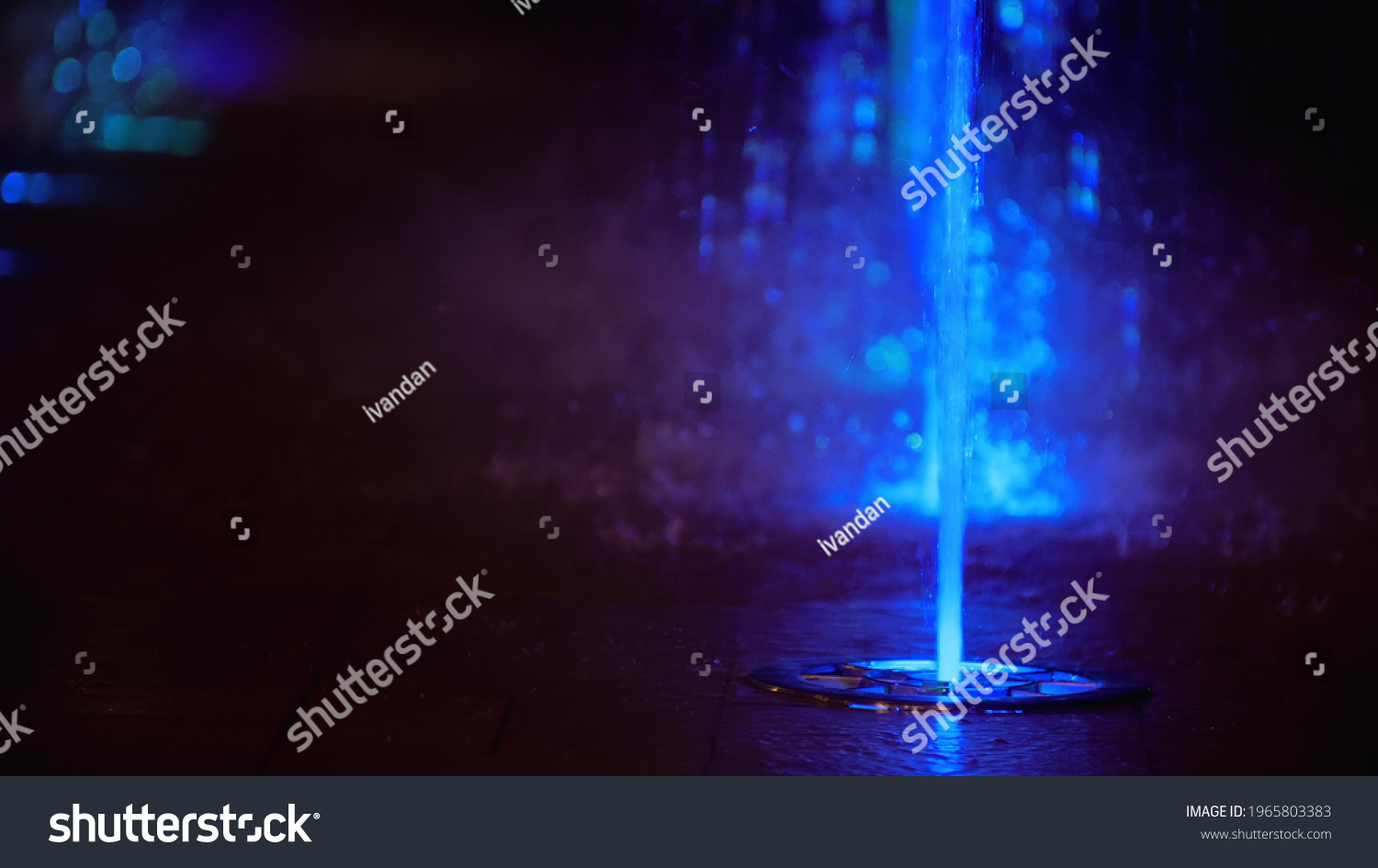 Splashes of colorful fountain. Water illuminated in diverse colors falling on a fountain which change its water color in the night. #1965803383