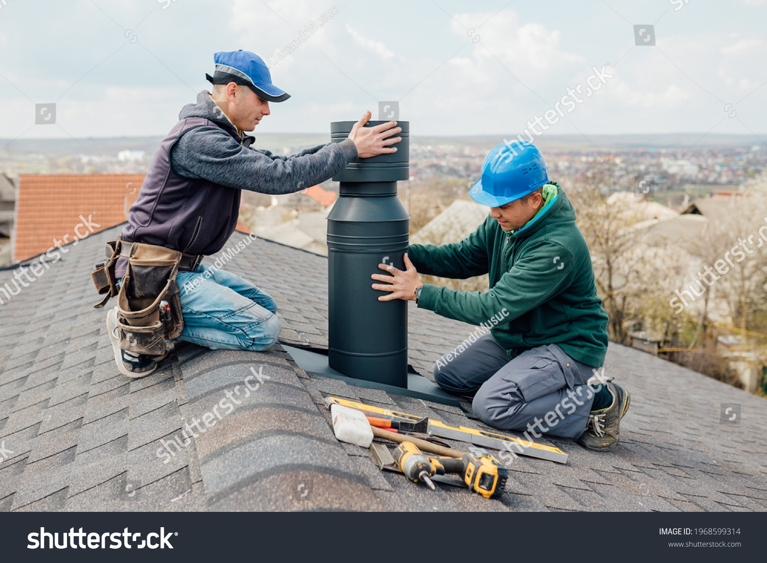 two Professional workmen's standing roof top and measuring chimney of new house under construction against blue background #1968599314