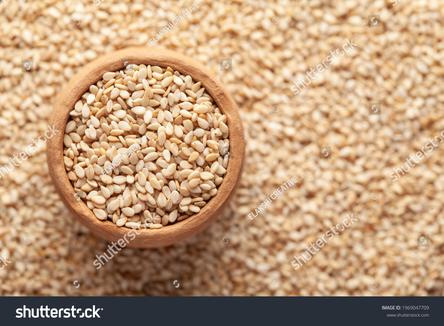 Macro Close-up of Organic White Sesame seeds(Sesamum indicum) or white Til in an earthen clay pot (kulhar) on the self background. Top view
 #1969047709