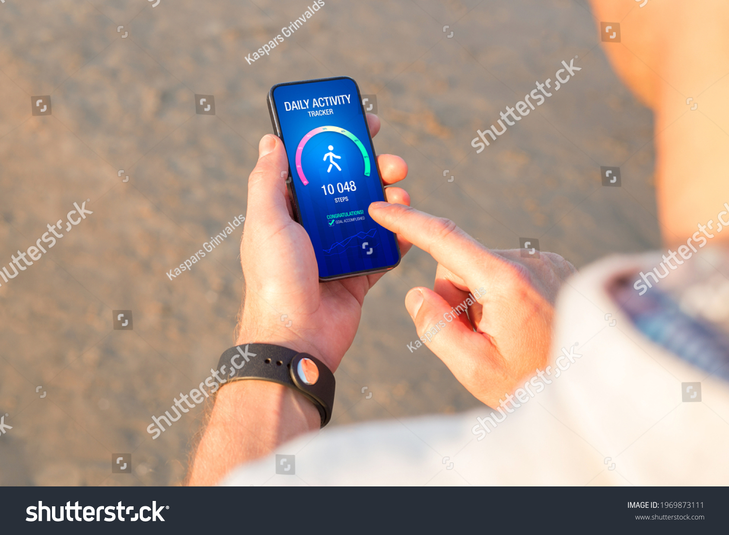 Man using daily activity tracking app on mobile phone showing 10 000 steps daily goal achievement #1969873111