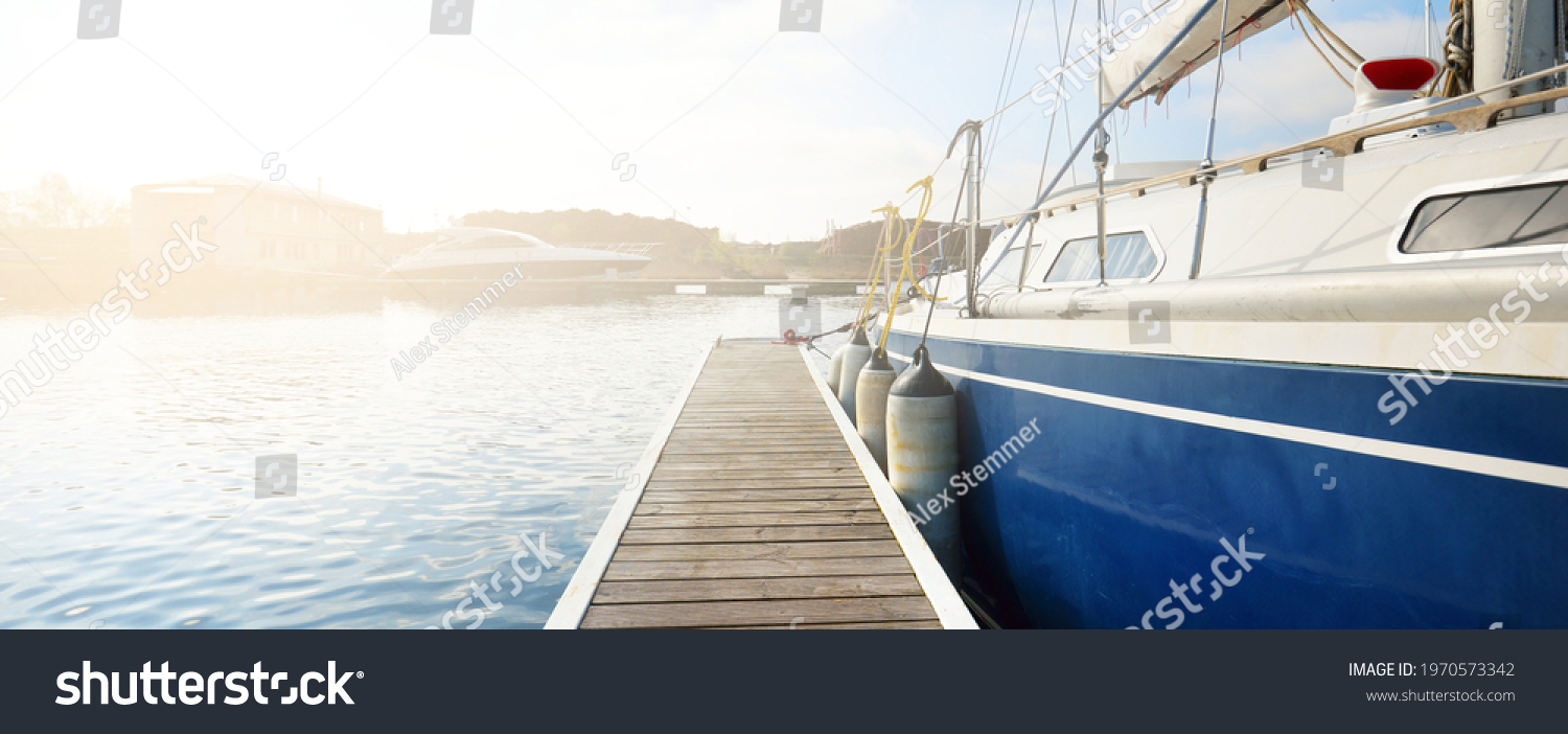 Elegant and modern sailing boats (for rent) moored to a pier in a yacht marina on a clear day. Sweden. Blue sloop rigged yacht close-up. Vacations, sport, amateur recreational sailing, cruise #1970573342
