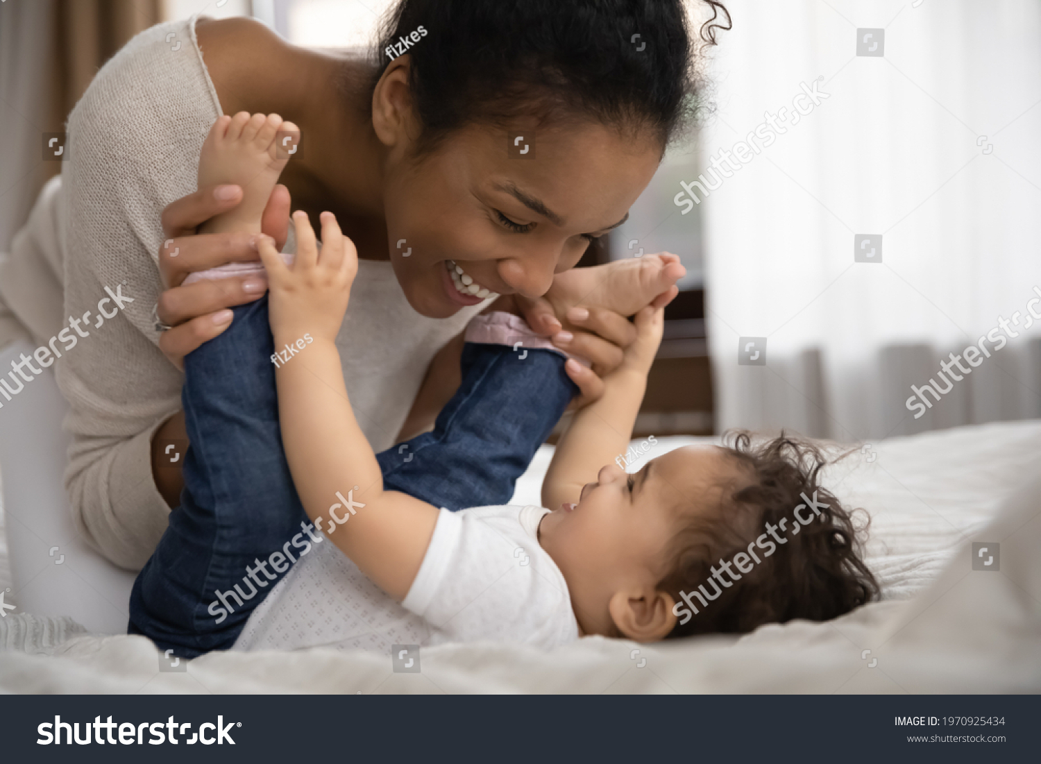 Overjoyed young African American mother relax play with smiling small biracial toddler daughter. Happy loving ethnic mom have fun enjoy motherhood with little baby girl child. Parenthood concept. #1970925434