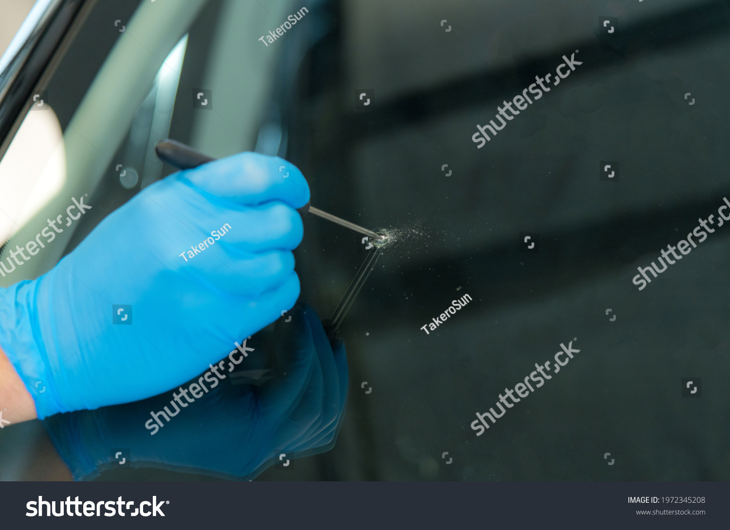 Mechanic is expanding a stone chip in a car windscreen before repairing #1972345208