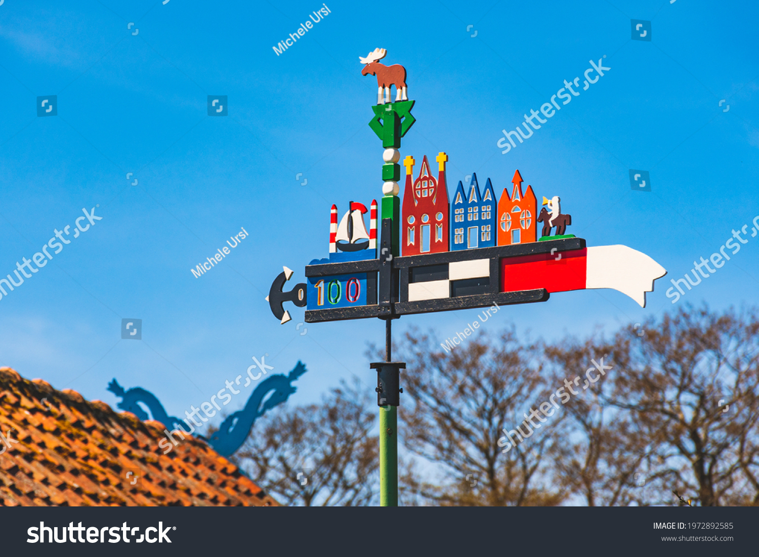 Beautiful colorful weathercock waving in the Curonian Spit in Nida fishermen's village, Lithuania, Europe with blue sky and roof with heads of horses on background  #1972892585