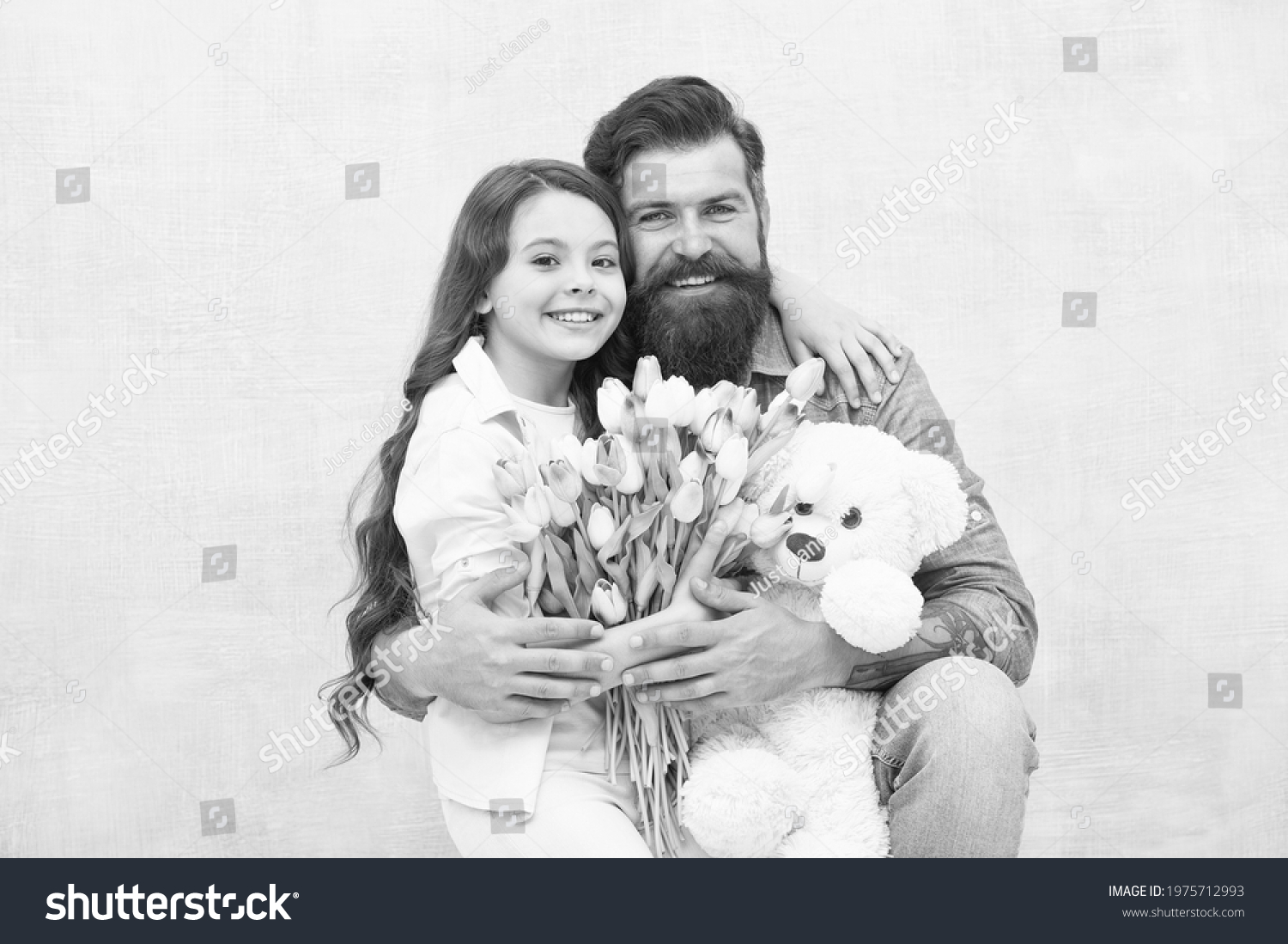 Fabulous gift for little one. Happy family celebrate holiday. Little child and bearded man hold flowers and toy. Small daughter hug father. Gift store. Toyshop. Floral shop. Birthday gift #1975712993
