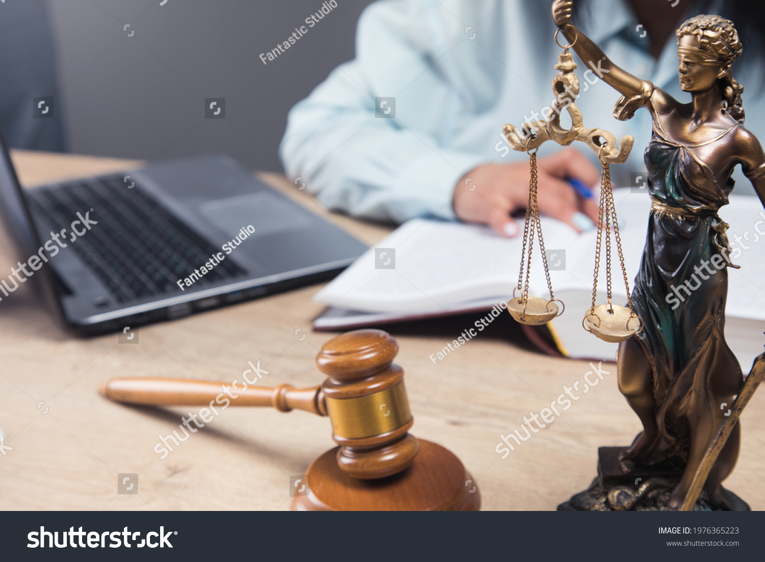 the judge sits in front of the gavel and statues of justice #1976365223