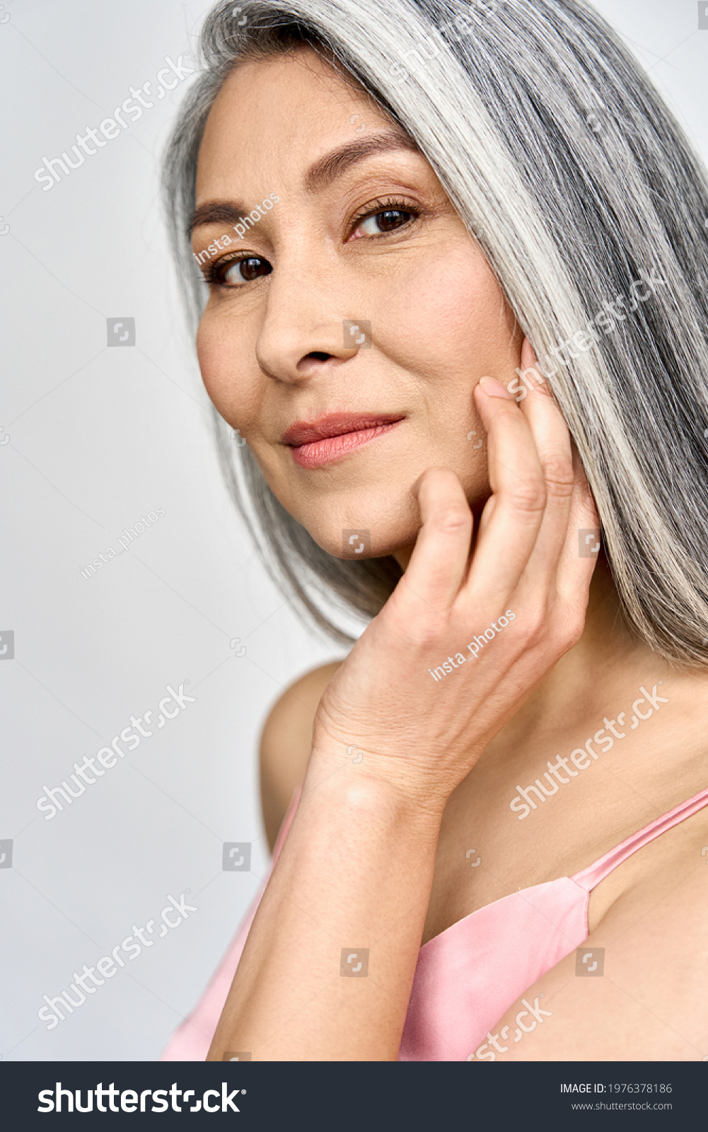 Vertical portrait of gorgeous happy middle aged mature asian woman, senior older 50 year lady looking at camera touching her face isolated on white. Ads of lifting anti wrinkle skin care, spa. #1976378186