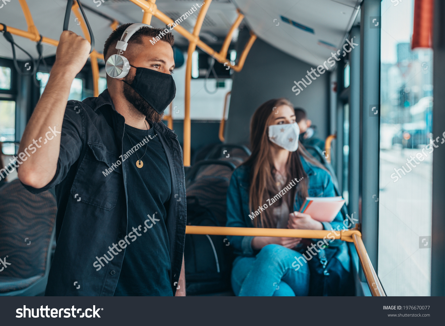 Passengers wearing protective mask while riding a bus and keeping the distance due to a corona virus pandemic #1976670077
