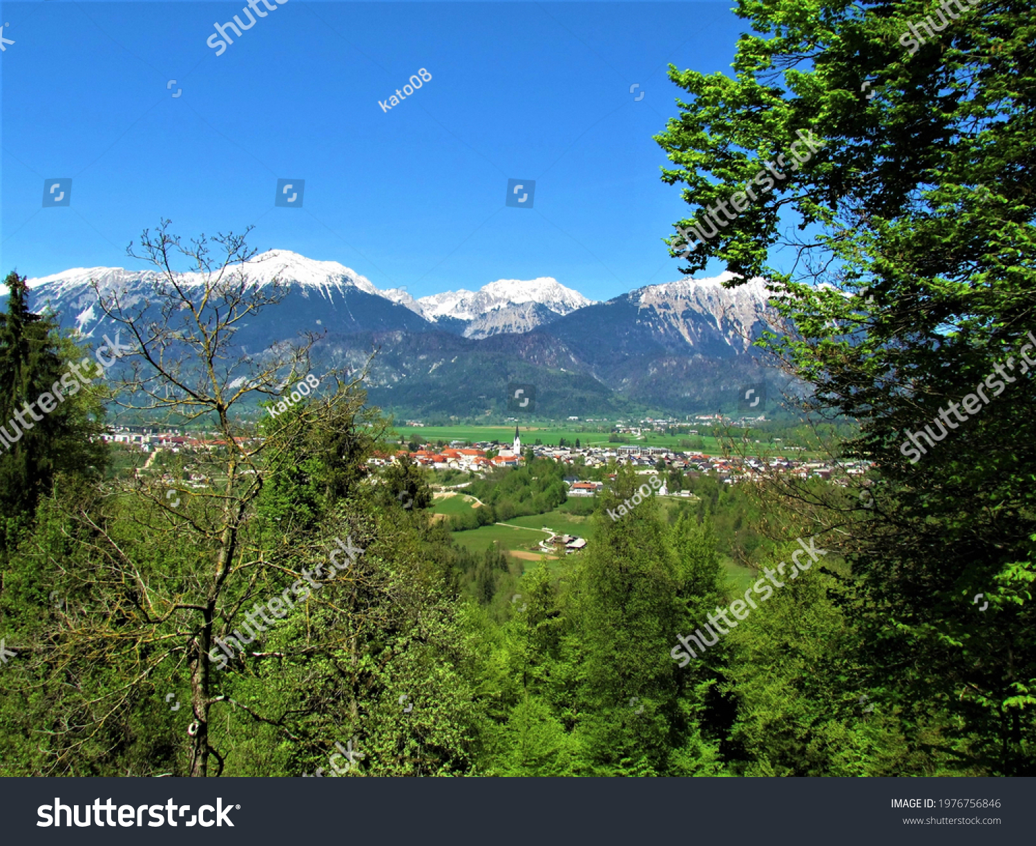 Beautiful view of the town of Radovljica in Gorenjska, Slovenia and snow covered peak of Karavanke mountains with trees in  front #1976756846