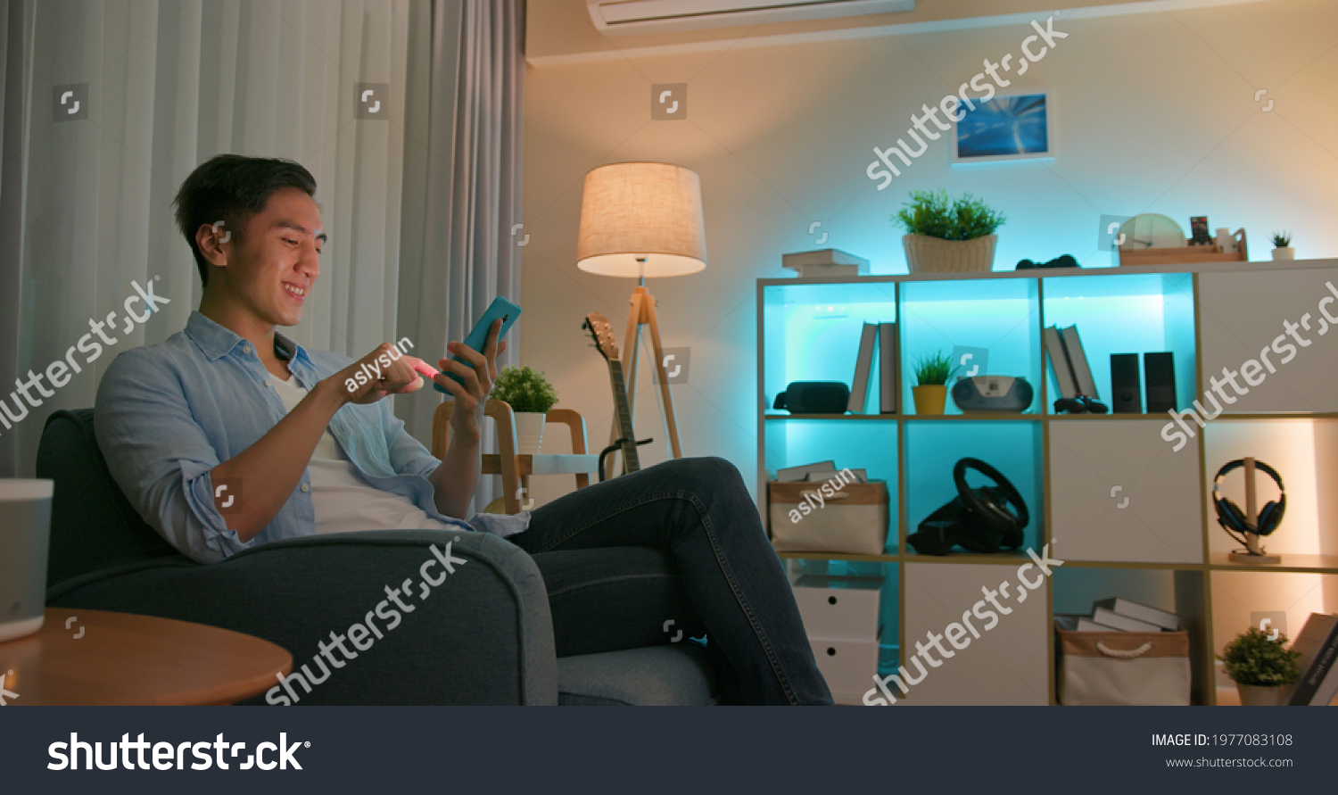 asian young man using smart home app to control light colors in the evening at home #1977083108