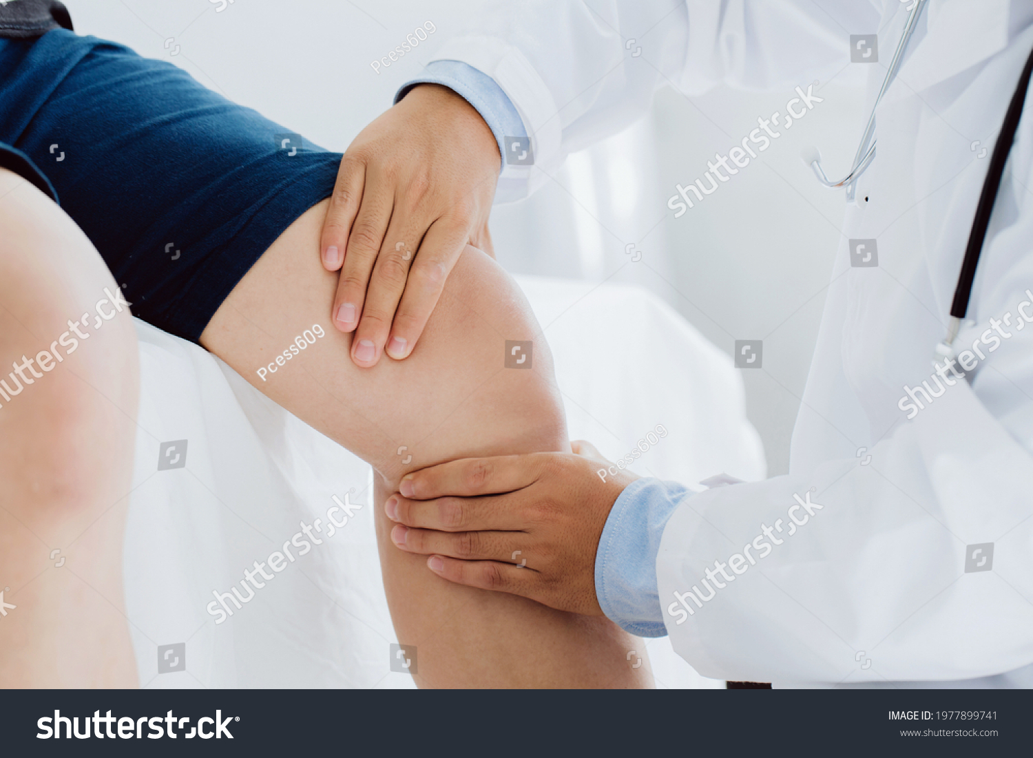 Doctor physiotherapist working examining treating injured knee of patient, his using the handle to the patient knee to check for pain. #1977899741