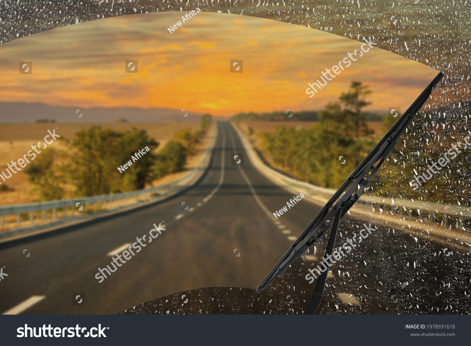 Car windshield wiper cleaning water drops from glass while driving #1978931618