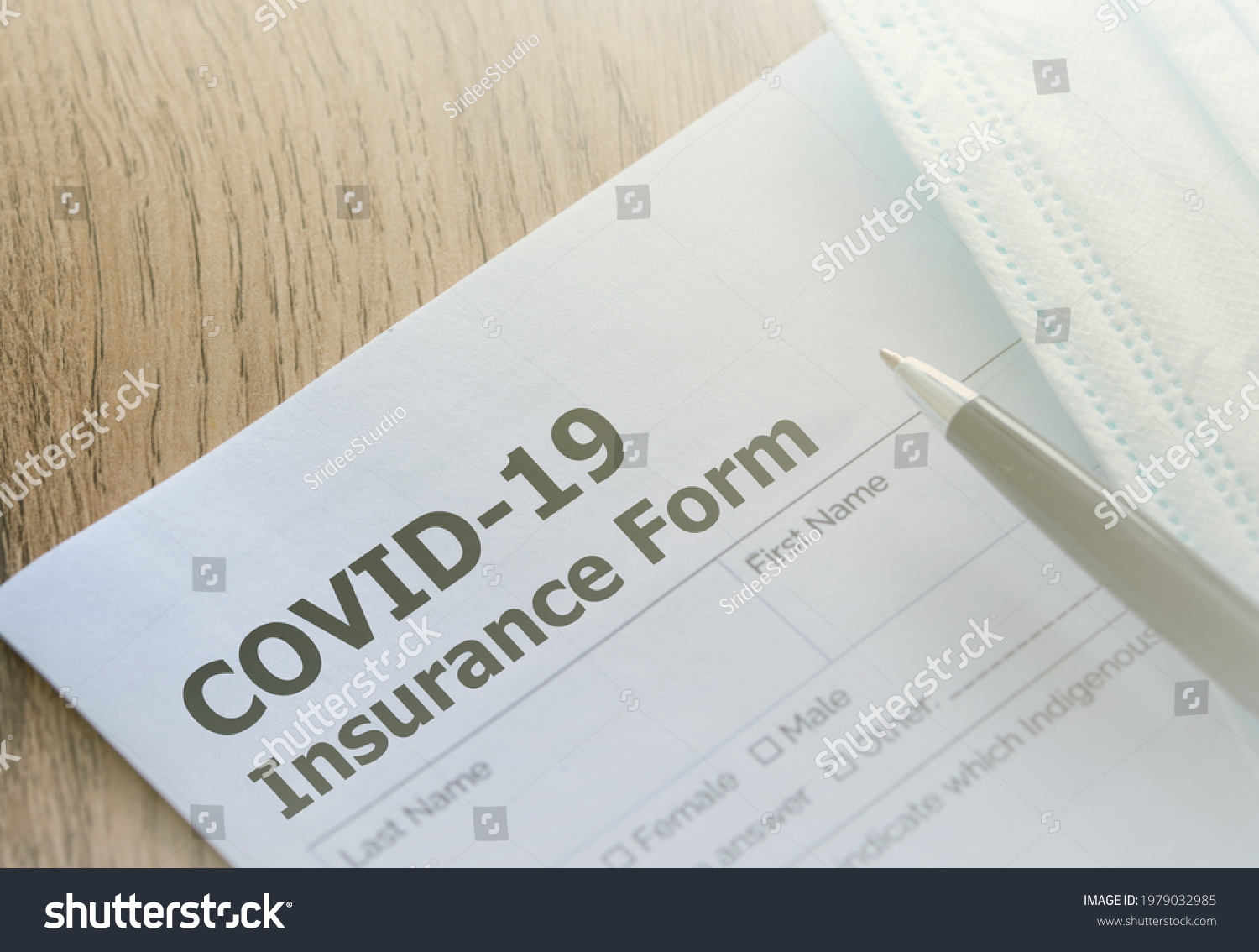 COVID-19 Health insurance paper form with a pen and medical mask on wooden table. Health insurance concept.  #1979032985