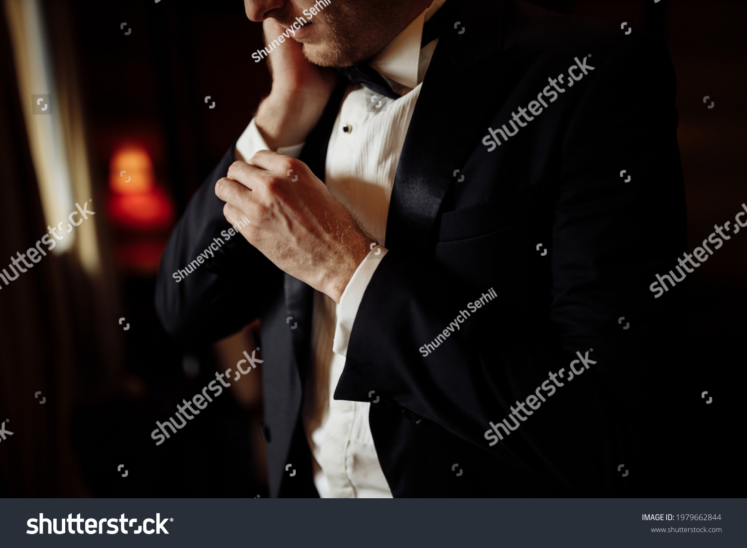 A close-up of a cropped frame of a man groom in an expensive classic costume and white shirt getting ready for event. The future husband is in a hurry and dressing up for wedding celebration. #1979662844