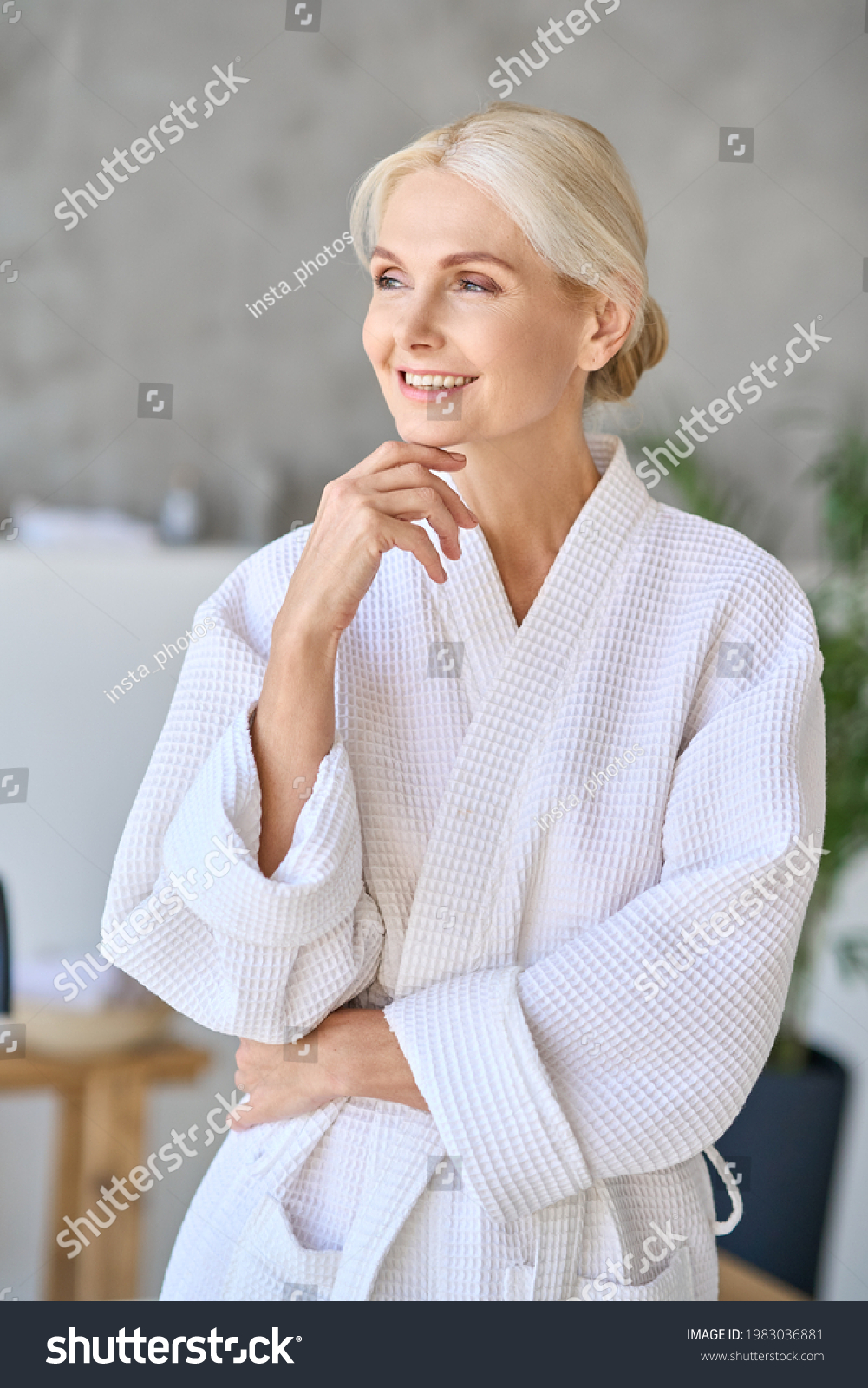 Happy smiling gorgeous senior aged woman in bathrobe at spa hotel looking away. Advertising of bodycare spa procedures recreation rejuvenation skin care salon concept. Vertical shot. #1983036881