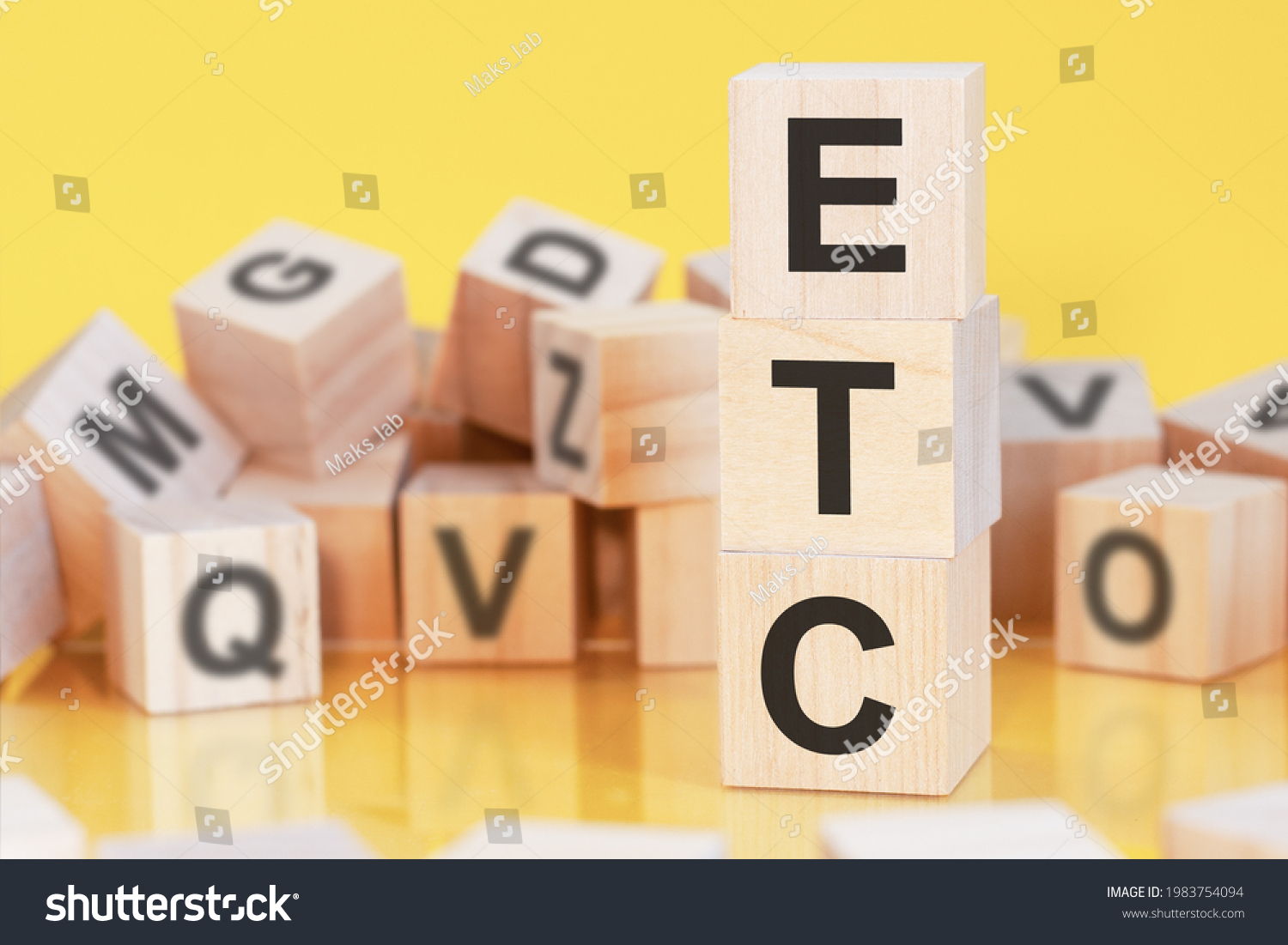 wooden cubes with letters ETC arranged in a vertical pyramid, yellow background, reflection from the surface of the table, business concept. etc - short for electronic trade confirmation #1983754094