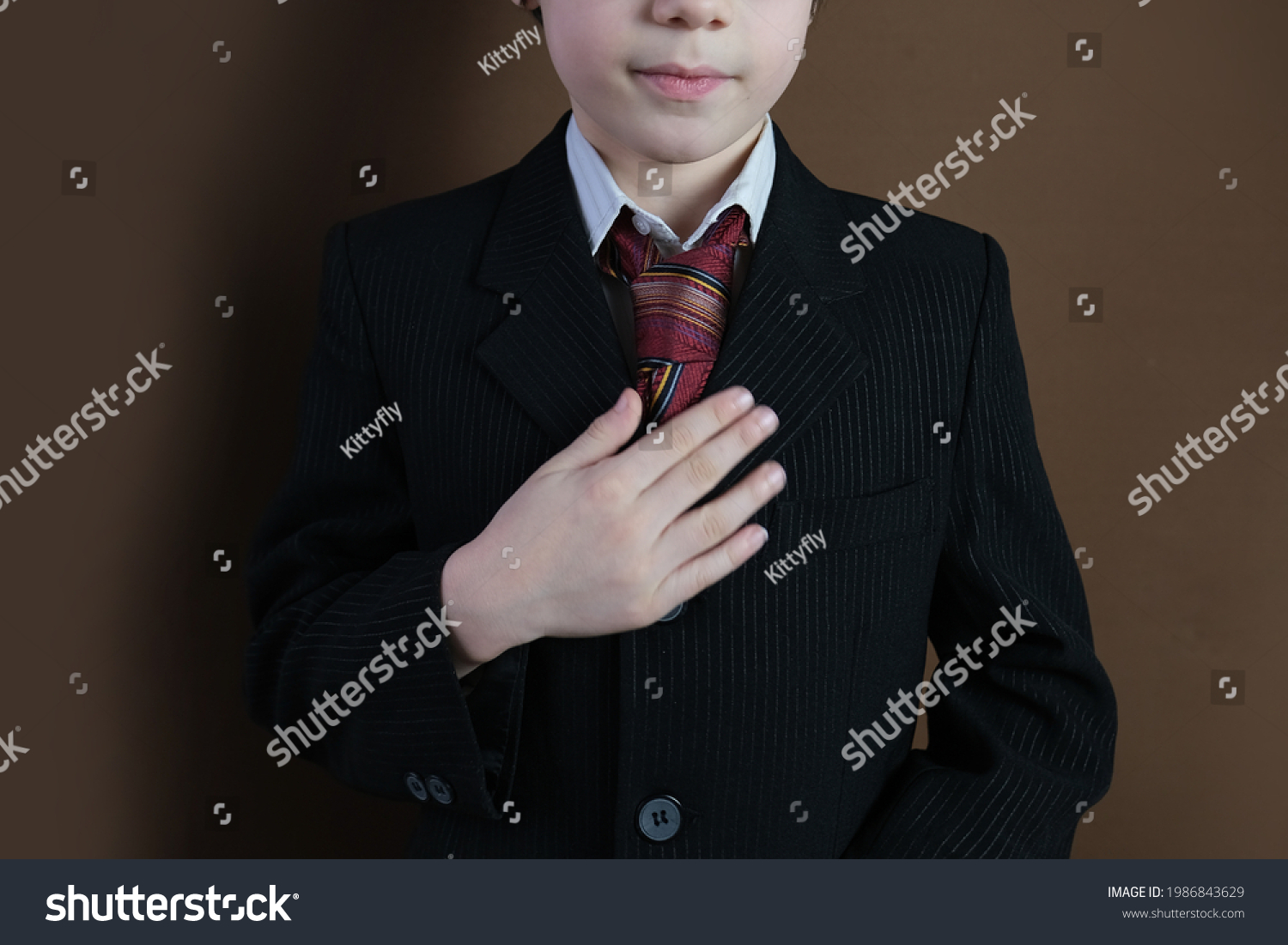 close-up of the lower part of the head of a child 8-10 years old, kid in a black business suit, tie smiling, formal uniform, concept of a young businessman, performance #1986843629