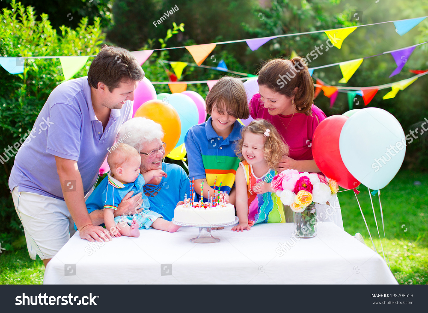 Happy big family - young parents, grandmother, three kids, teenage boy, toddler girl and little baby celebrating birthday party with cake and candles in the garden decorated with balloons and banners #198708653