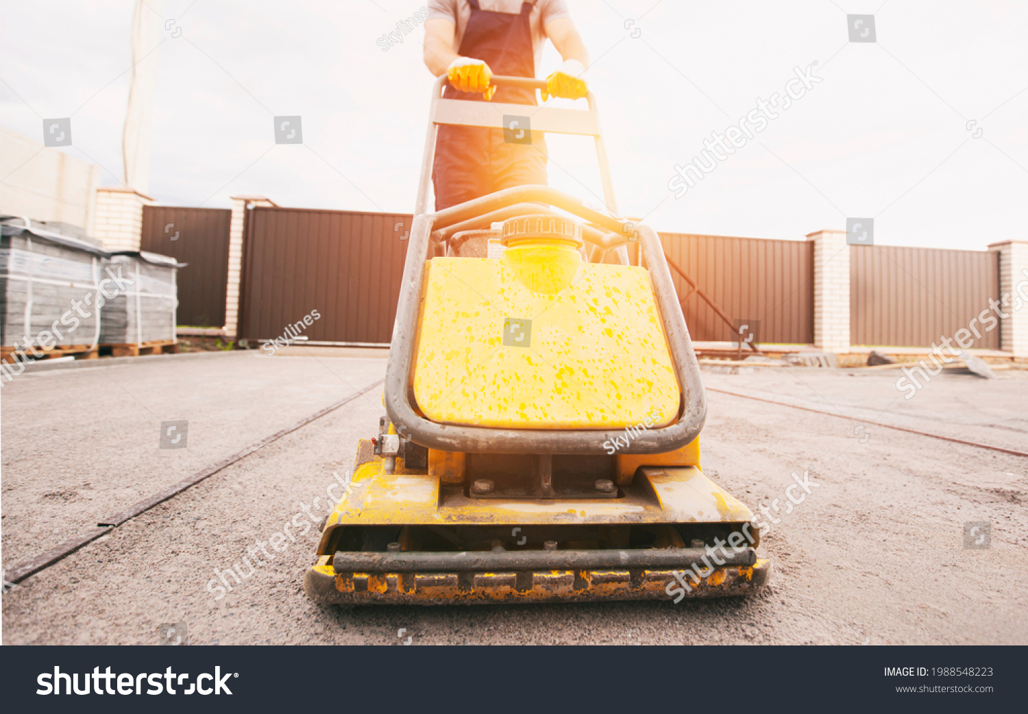 The worker tamping a gravel by the vibration plate #1988548223