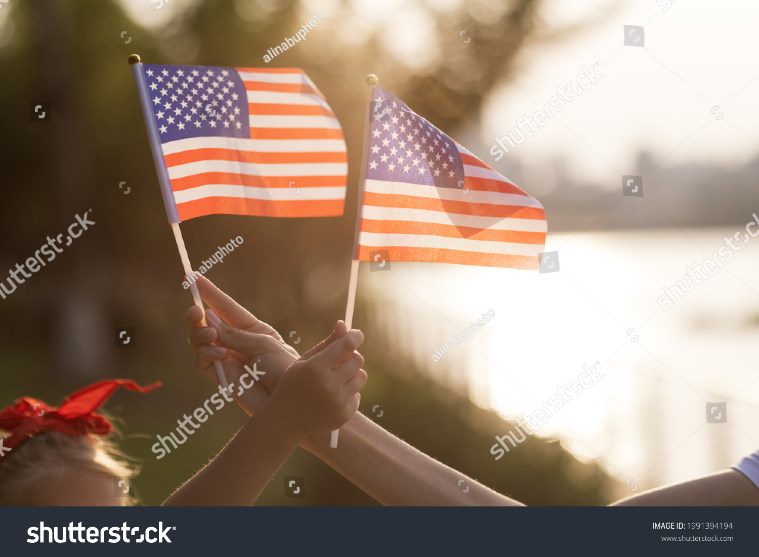 Patriotic holiday. Happy family, mother and daughter with American flag outdoors on sunset. USA celebrate independence day 4th of July. #1991394194