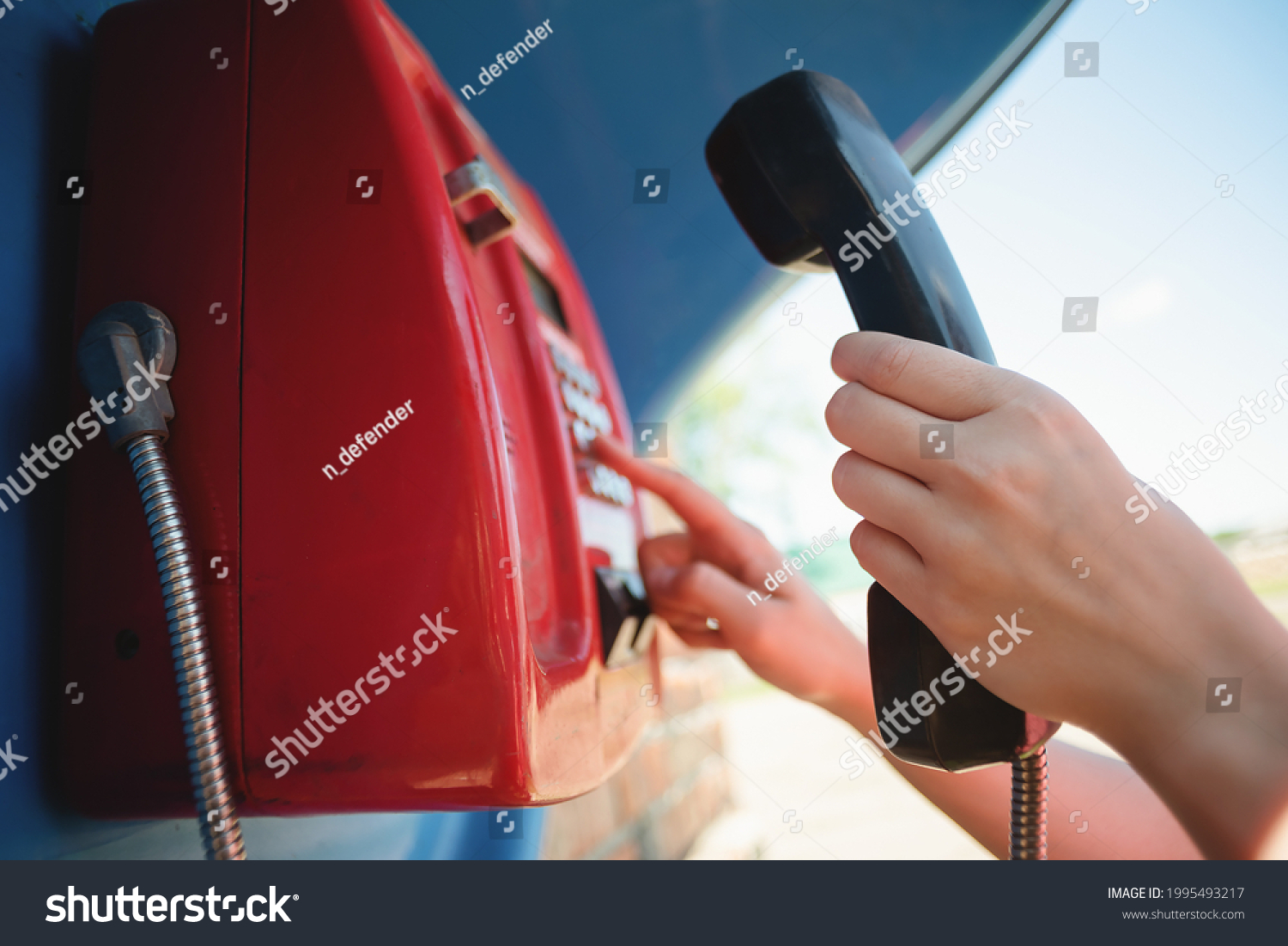 Woman is calling by the public payphone close up. #1995493217