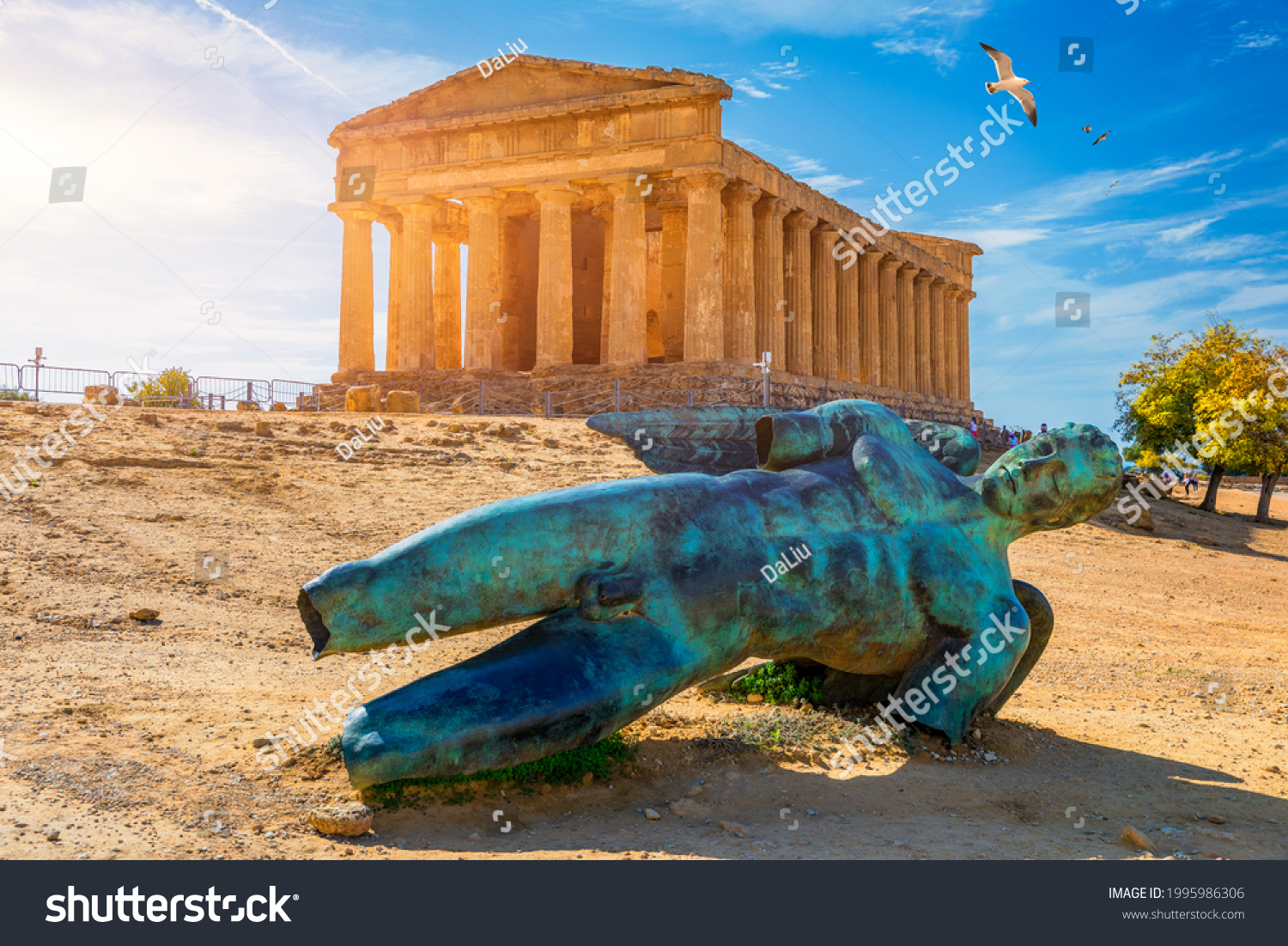 Bronze statue of Icarus in front of the Temple of Concordia at the Valley of the Temples. Temple of Concordia and the statue of Fallen Icarus, in the Valley of the Temples, Agrigento, Sicily, Italy. #1995986306