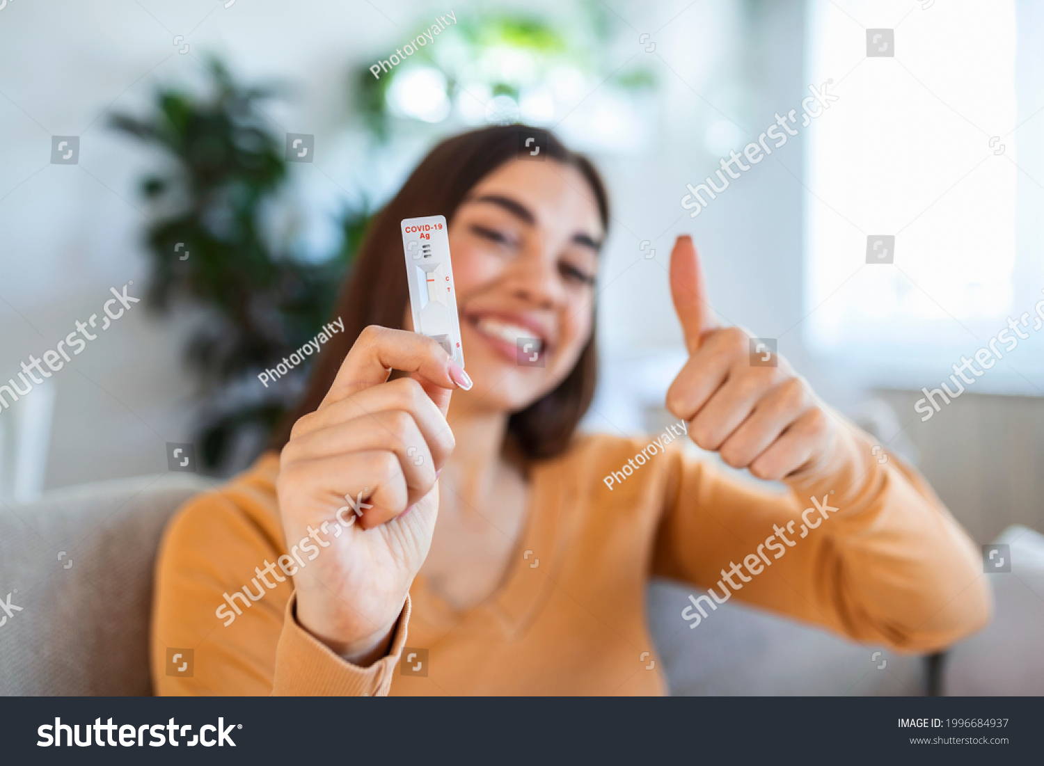 Close-up shot of woman's hand holding a negative test device. Happy young woman showing her negative Coronavirus - Covid-19 rapid test. Focus is on the test.Coronavirus #1996684937