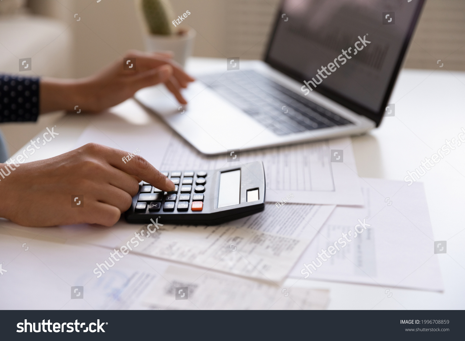 Crop close up of Indian woman manage household expenses expenditures calculate on machine pay on computer online. Ethnic female make web payment consider budget finances at home. Banking concept. #1996708859