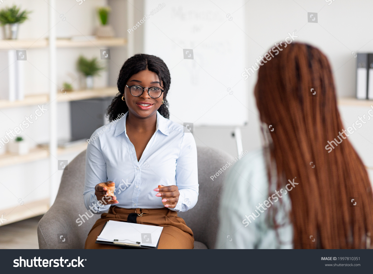 Psychotherapy consultation. Counselor talking to black woman on meeting at office, giving advice to young client. Friendly African American psychologist having session with female customer #1997810351