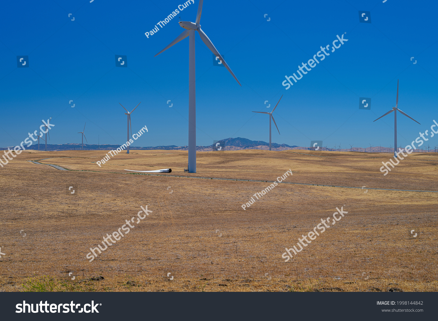 Windustry, an airfoil lays on the ground afoot of a wind turbine on the wind farm. #1998144842