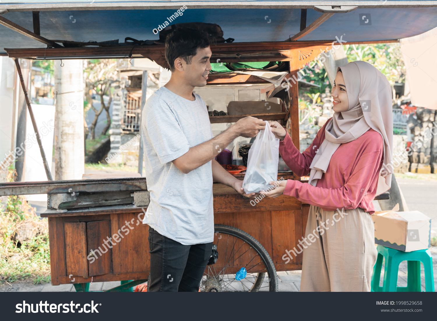muslim woman ordering chicken satay from small food cart seller. sate ayam street food #1998529658